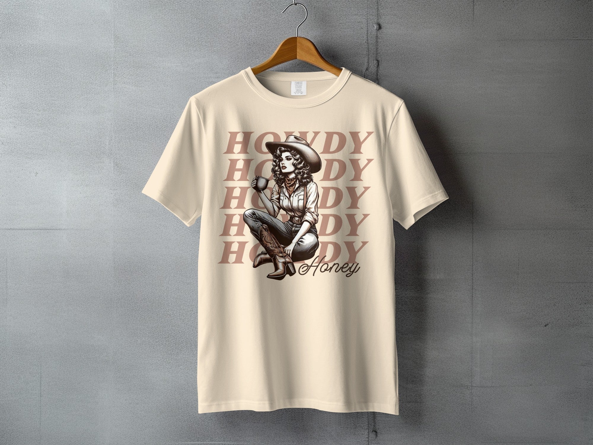 Cowgirl holding coffee mug, "Howdy Honey" text on tan t-shirt.