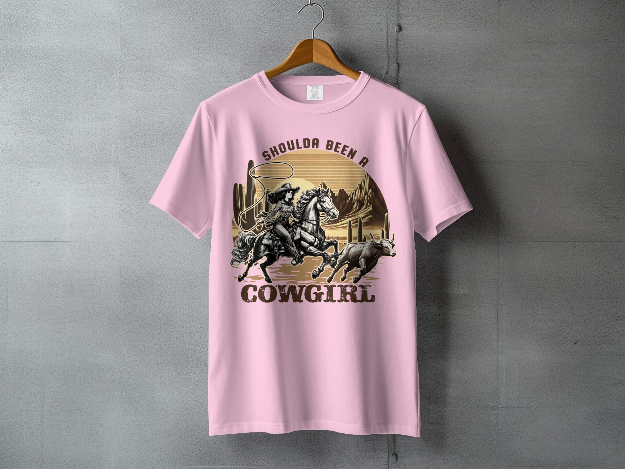 T-shirt graphic: cowgirl roping a bull in a desert landscape.