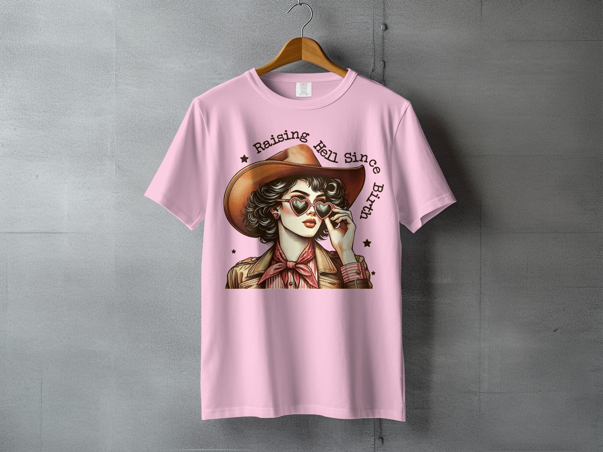 Cowgirl with heart sunglasses and text "Raising Hell Since Birth".