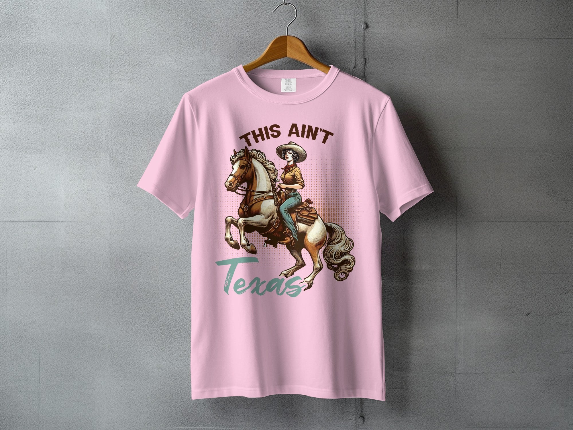 Pink t-shirt with woman on horseback and "THIS AIN'T Texas" text.