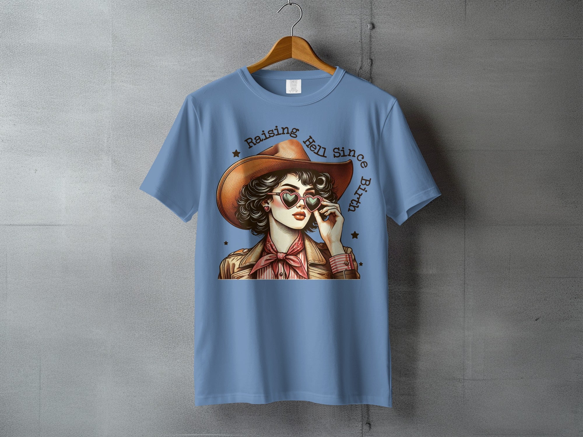 Cowgirl wearing heart-shaped sunglasses, "Raising Hell Since Birth" text.