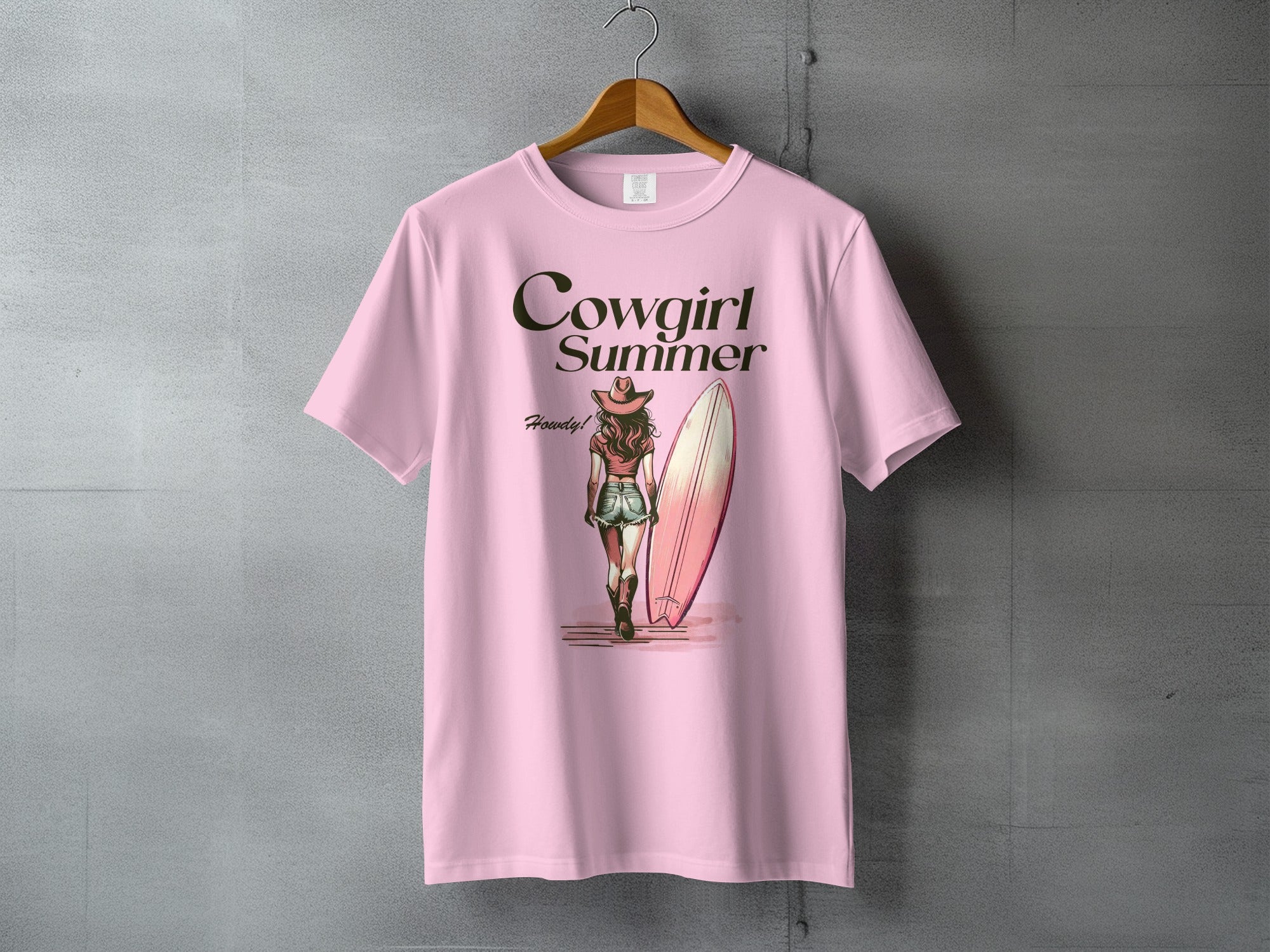 Pink t-shirt with "Cowgirl Summer" text and woman with surfboard illustration.