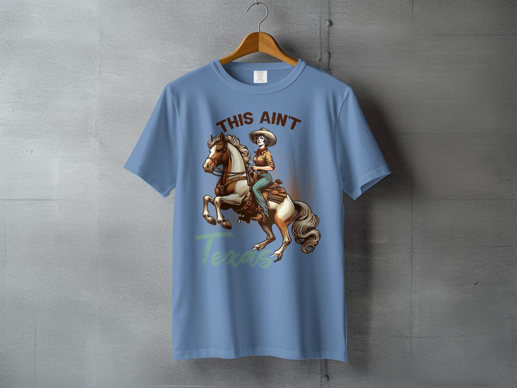 Light blue t-shirt with graphic of woman on horse and text "This Ain't Texas".