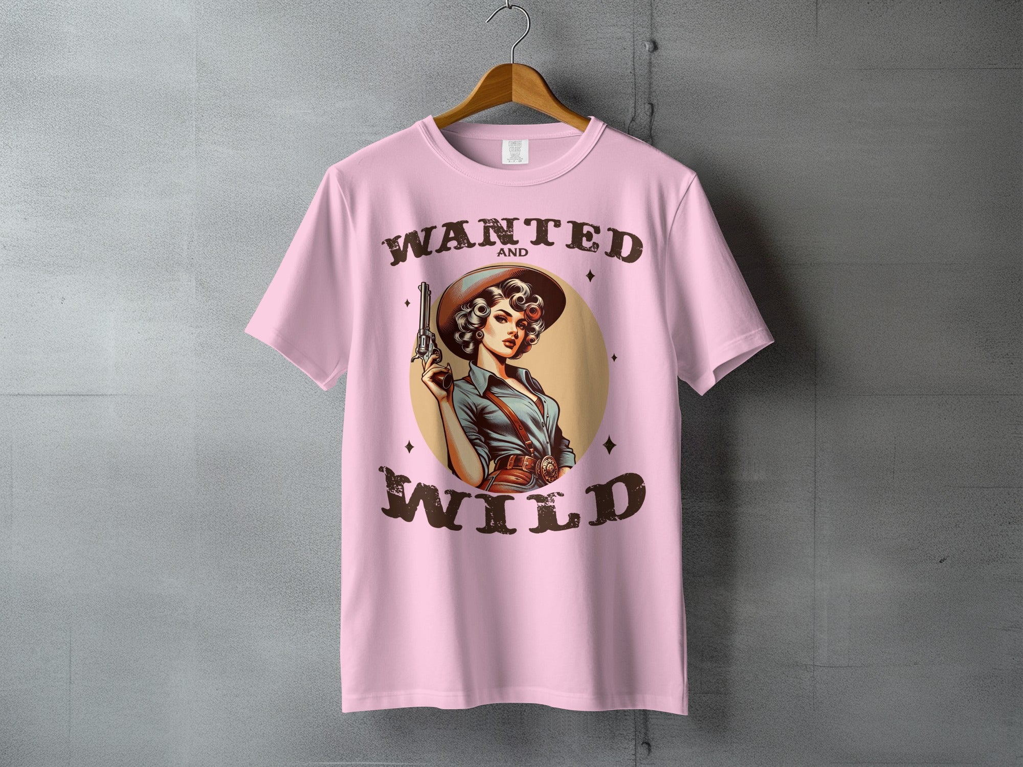 Pink t-shirt graphic: Woman in cowboy hat and Western wear holding a pistol, "Wanted and Wild".