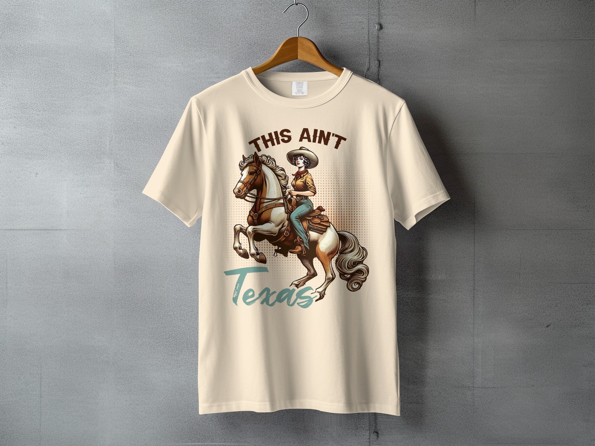 Cream t-shirt with graphic of cowgirl on horse, reads "This Ain't Texas".