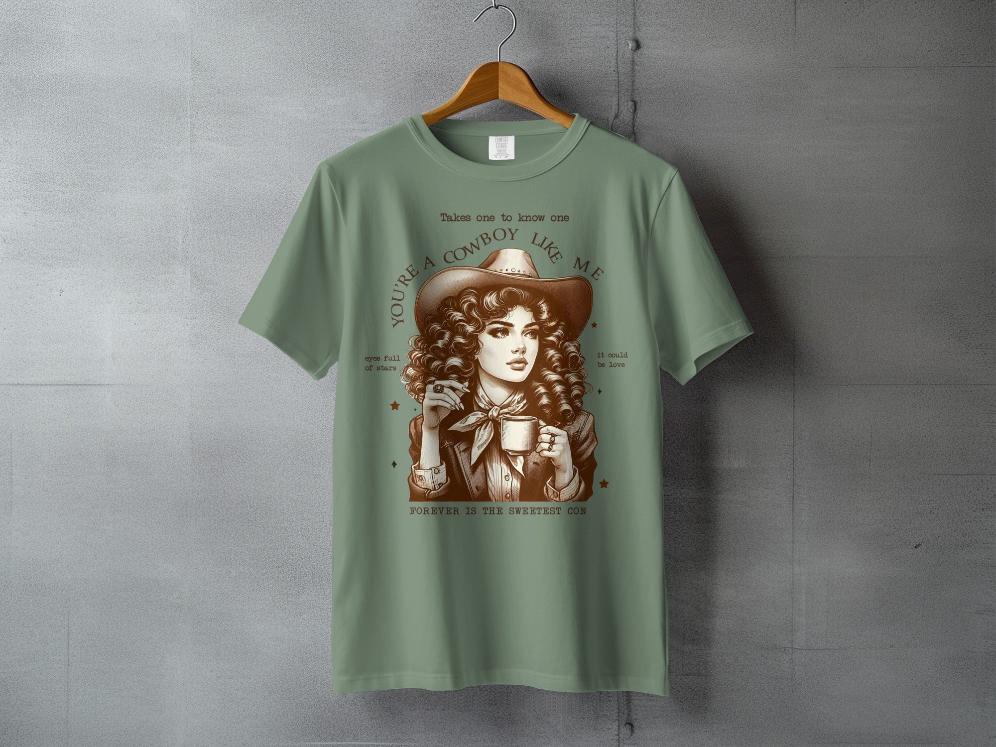 T-shirt with woman in cowboy hat holding mug, text "Takes one to know one 'RE A COWBOY LIKE ME".